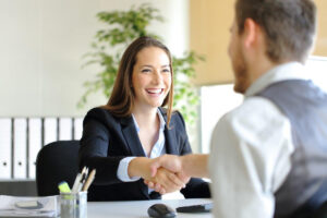 a man and a woman shaking hands sitting at a table