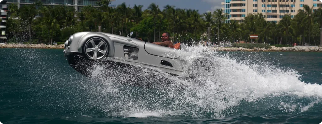 Silver luxury watersports car, two seats, speed boat, riding the waves. Series M with a man enjoying the ride. Available at Pier One Yacht Sales